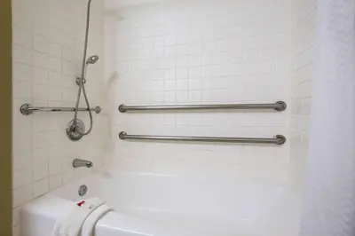 a bathroom with a tub and a white tiled wall at Baymont by Wyndham Tehachapi in Tehachapi