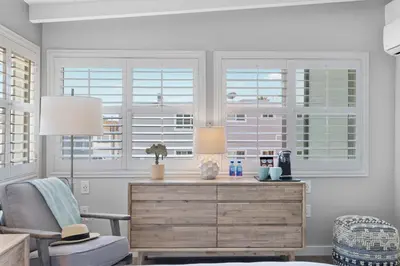 a living room with a dresser and two windows at Sea Sprite Beach Club in Hermosa Beach