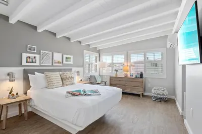 a bedroom with a white bed and a desk at Sea Sprite Beach Club in Hermosa Beach