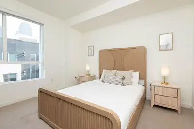 a white bedroom with a large bed and a window at Modern Apartment Rentals in Los Angeles