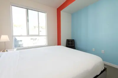 a white bed in a room with a window at Modern Apartment Rentals in Los Angeles