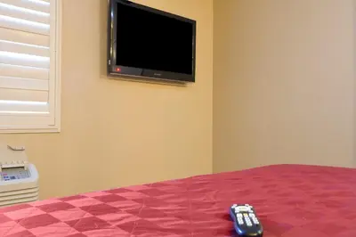 a remote control sitting on a bed with a tv on the wall at Covina Motel in West Covina