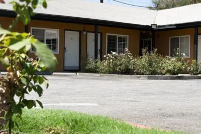 a building with a parking lot and some flowers at Covina Motel in West Covina