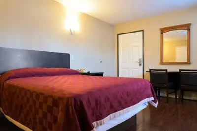 a bedroom with a bed and a mirror and a chair at Covina Motel in West Covina