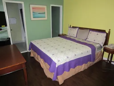 a bedroom with a bed with a purple comforter at Travel Eagle Inn Motel in Long Beach