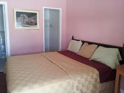 a bedroom with a bed with pink walls at Travel Eagle Inn Motel in Long Beach