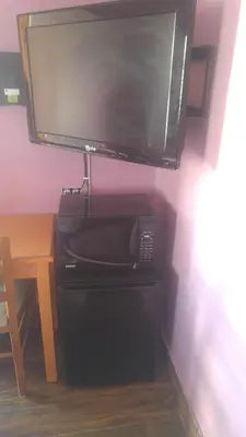 a television hanging on a wall with a microwave at Travel Eagle Inn Motel in Long Beach