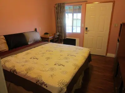 a bedroom with a bed and a window and a door at Travel Eagle Inn Motel in Long Beach