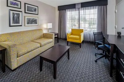 a hotel room with a couch and a desk and a chair at La Quinta by Wyndham Anaheim in Anaheim