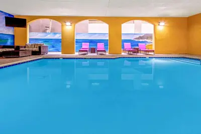 a large swimming pool in a hotel room with pink chairs at La Quinta by Wyndham Anaheim in Anaheim