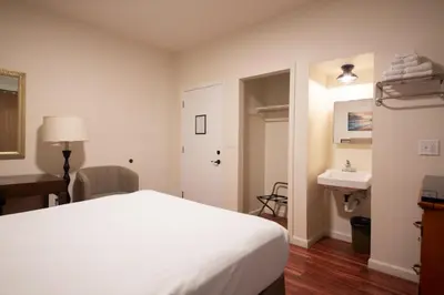 a bedroom with a white bed and a sink at Anchor Pointe Inn in Wilmington