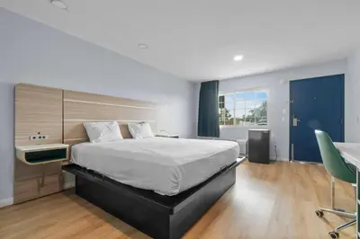 a bedroom with a bed and a desk and a chair at Travelodge by Wyndham Fairplex Pomona in Pomona