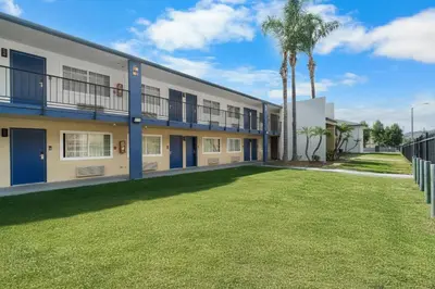 an apartment building with a lawn in front of it at Travelodge by Wyndham Fairplex Pomona in Pomona