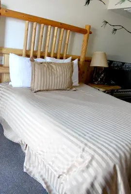 a large white bed with a wooden headboard in a bedroom at Fireside Lodge in Big Bear Lake