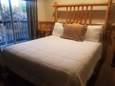 a bed with white sheets and pillows next to a window at Fireside Lodge in Big Bear Lake