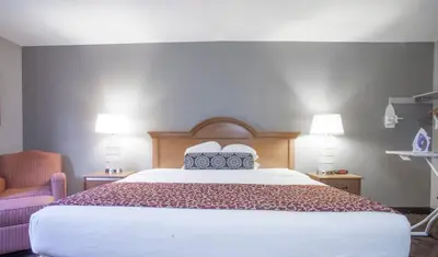 a bedroom with a large bed and a chair at Ramada by Wyndham Barstow in Barstow