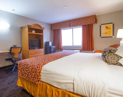 a hotel room with a large bed and a television at Ramada by Wyndham Barstow in Barstow