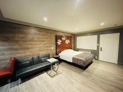 a bedroom with a bed and a black leather couch at Casa Blanca Inn - Whittier, Los Angeles in Whittier