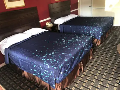 two beds in a hotel room with blue sheets at Whittier Travel Inn in Whittier