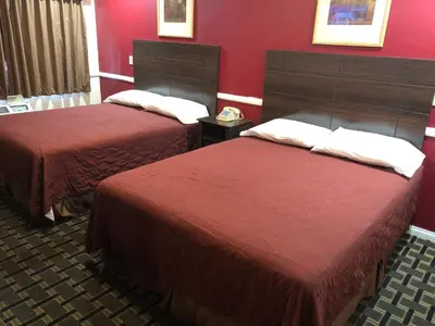 two beds in a hotel room with red walls at Whittier Travel Inn in Whittier