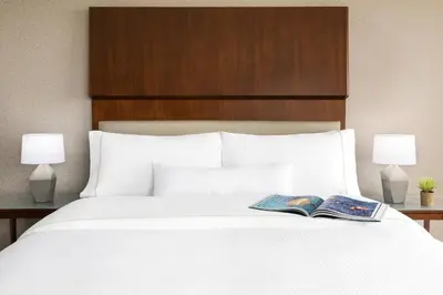 a bed with two lamps and a book on it at The Westin Long Beach in Long Beach