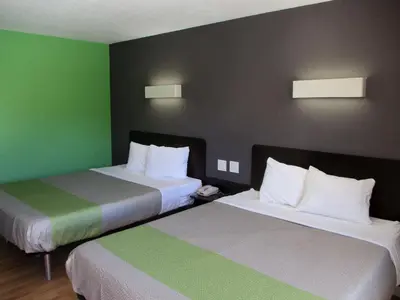 two beds in a hotel room with green walls at Studio 6-Barstow, CA in Barstow