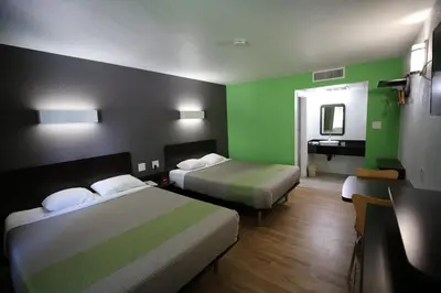 a hotel room with two beds with green walls at Studio 6-Barstow, CA in Barstow