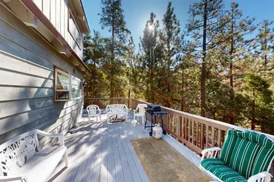 a deck with two green benches and chairs on it at Dancing Bear Chalet in Lake Arrowhead