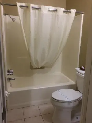 a bathroom with a toilet and a bath tub with a shower curtain at Holland Inn and Suites in Taft