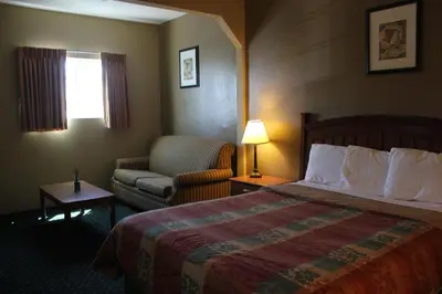a hotel room with a bed and a chair at Holland Inn and Suites in Taft