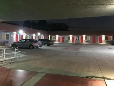a parking lot with two cars parked in front of a building at Rocky Inn Motel in Lynwood