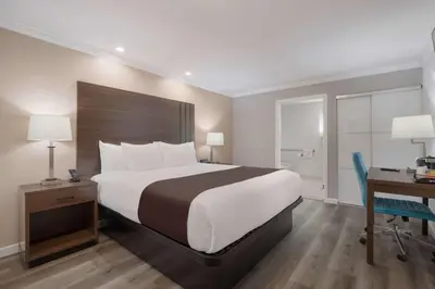 a hotel room with a large bed and a desk and a desk at SureStay Plus Hotel by Best Western Upland - Ontario North in Upland