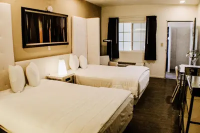a hotel room with two beds and a window at Devonshire Inn Motel in Rosamond