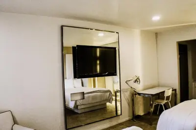 a mirror in a hotel room with a bed and a desk at Devonshire Inn Motel in Rosamond