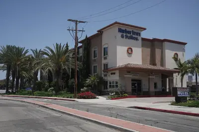 a hotel on the corner of a street with palm trees at Harbor Inn & Suites in Anaheim