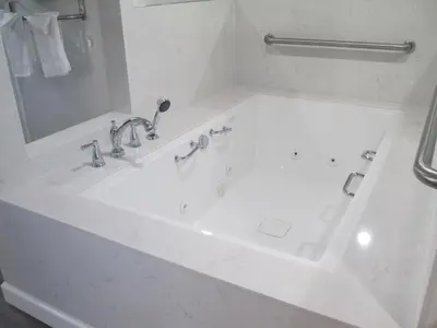 a white bathroom with a bath tub with a mirror at Claremont Lodge in Claremont