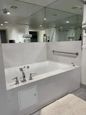 a bathroom with a bath tub with a large mirror at Claremont Lodge in Claremont