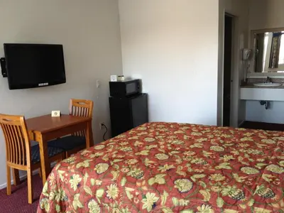 a hotel room with a bed and a table and a television at Scottish Inns in Long Beach