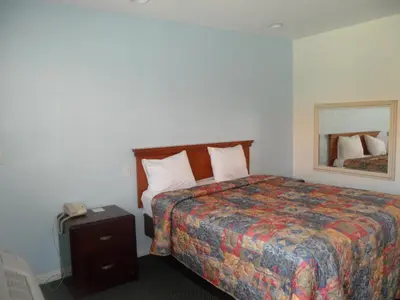 a hotel room with a bed and a night stand at Scottish Inns in Long Beach