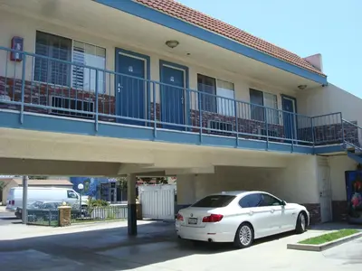 a white car parked in front of a building at Scottish Inns in Long Beach
