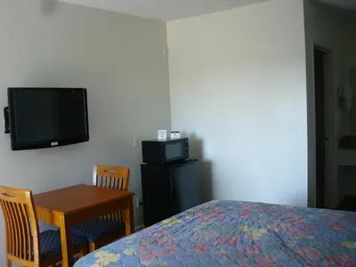 a bedroom with a bed and a table and a tv at Scottish Inns in Long Beach