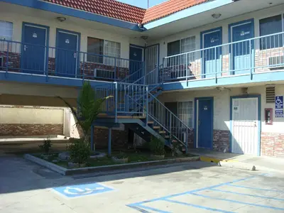 a building with blue doors and stairs in a parking lot at Scottish Inns in Long Beach