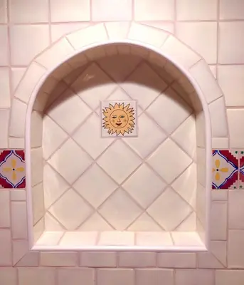 an arched niche in a white tile wall with a sun sticker at Ocean View Casita in Los Angeles