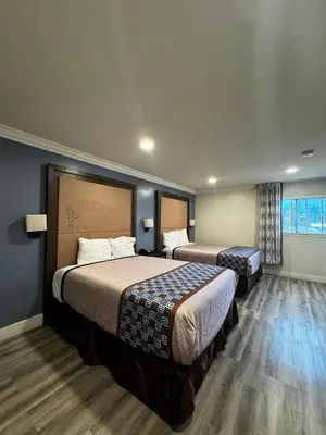 a hotel room with two beds and a window at Friendship Motor Inn in Los Angeles