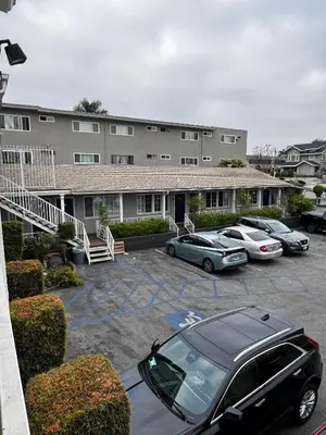 a group of cars parked in a parking lot in front of a building at Friendship Motor Inn in Los Angeles