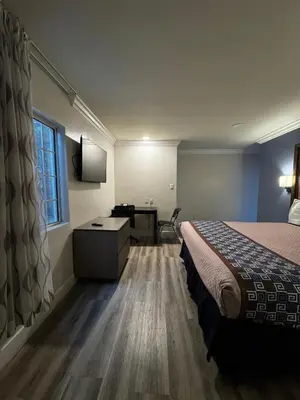 a hotel room with a bed and a desk at Friendship Motor Inn in Los Angeles