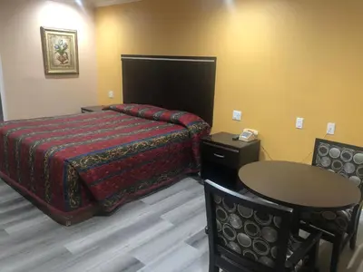 a hotel room with a bed and a table and chair at Economy Inn near Ontario Airport - Chino in Ontario