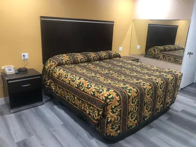 a hotel room with a bed with a blanket on it at Economy Inn near Ontario Airport - Chino in Ontario