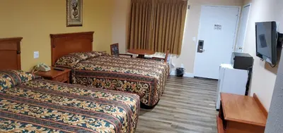 a hotel room with two beds and a flat screen tv at Economy Inn near Ontario Airport - Chino in Ontario
