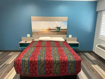 a bedroom with a bed and a painting of a beach at Sahara Inn - Los Angeles in Los Angeles